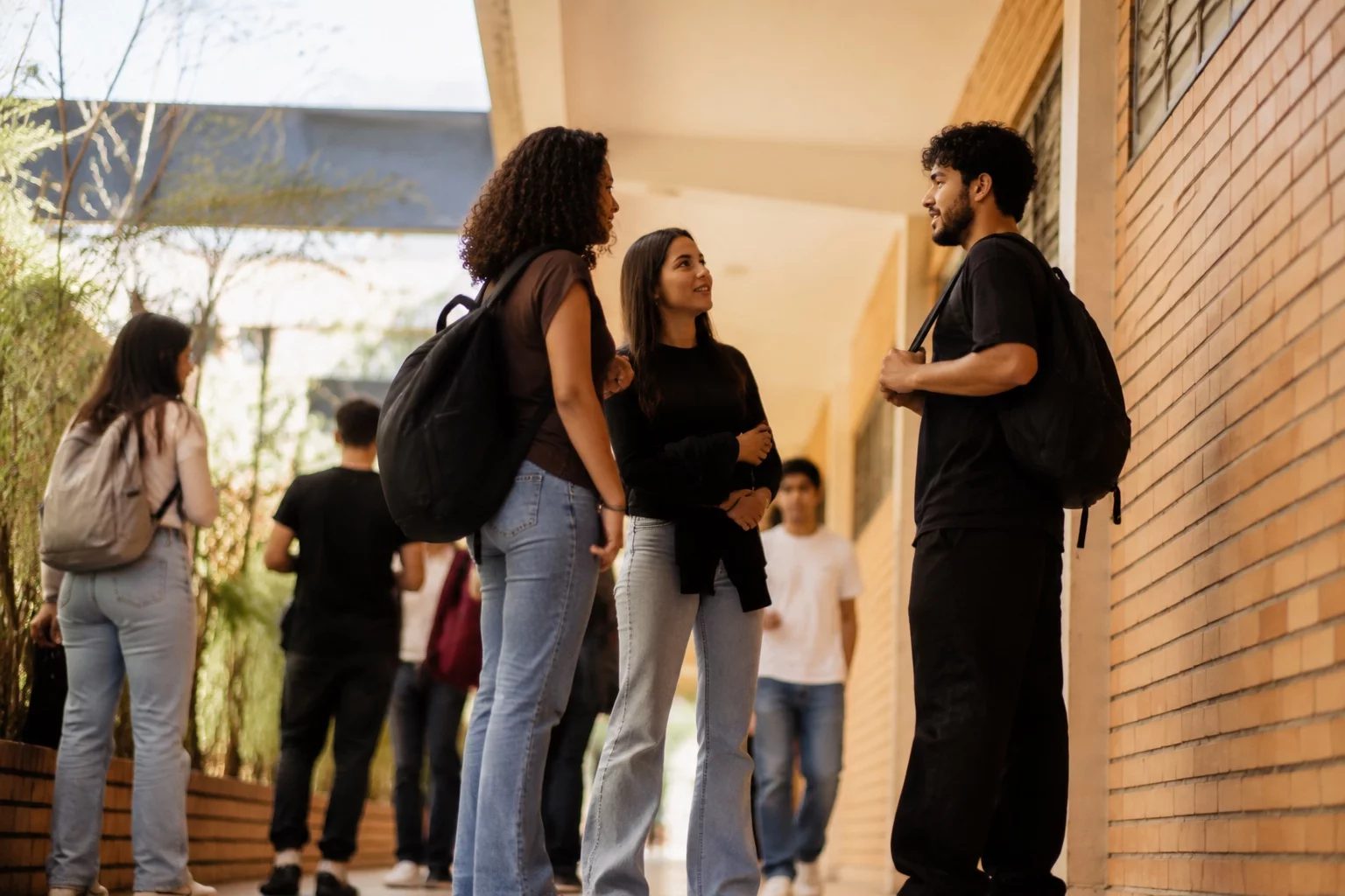 Estudantes com mochilas conversando no corredor de uma universidade