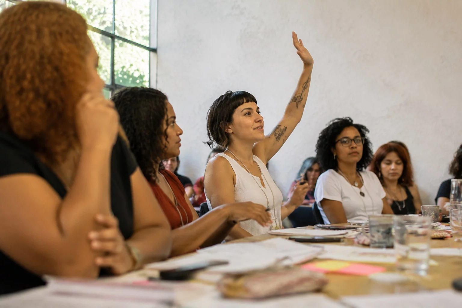 Estudante levantando a mão em uma mesa de seminário coberta de anotações